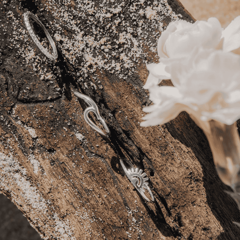Silver earrings on a wooden surface with a white flower