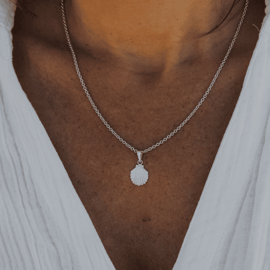 silver shell pendant on womans neck