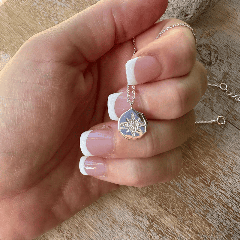 hand holding a silver pendant