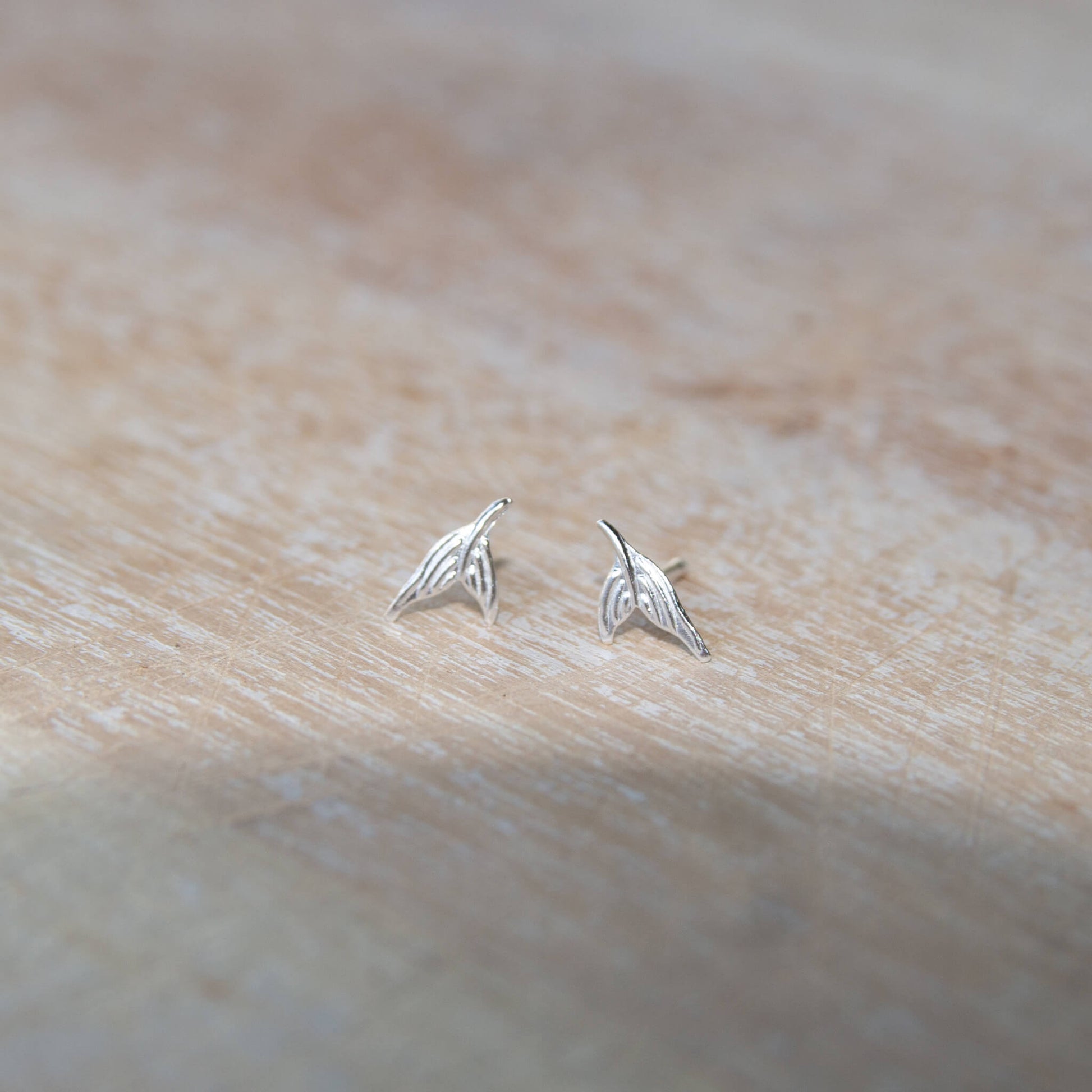 Sterling Silver Mermaid Tail Stud Earrings on a table