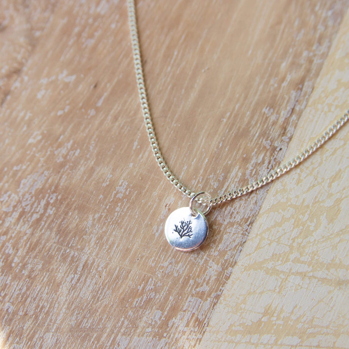 silver pendant necklace with a coral stamp