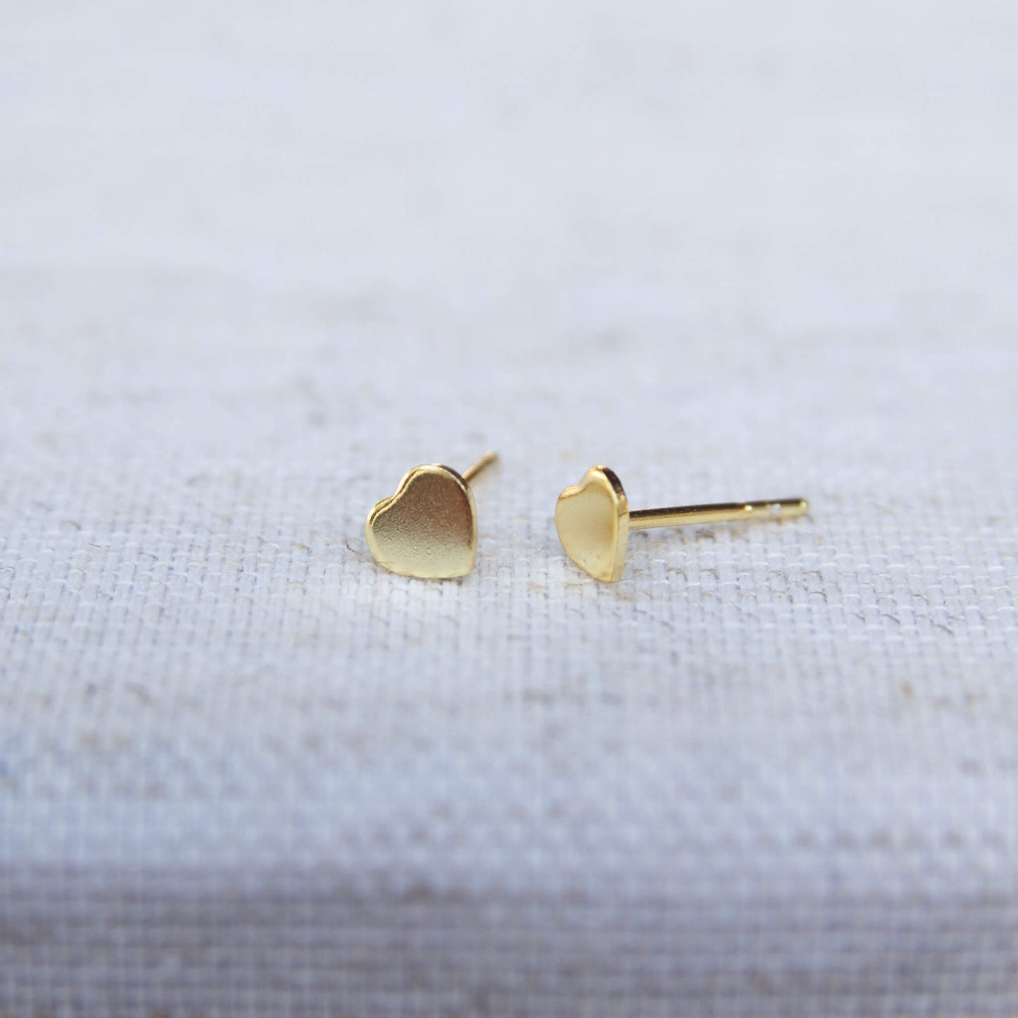 gold stud love heart earrings on grey background