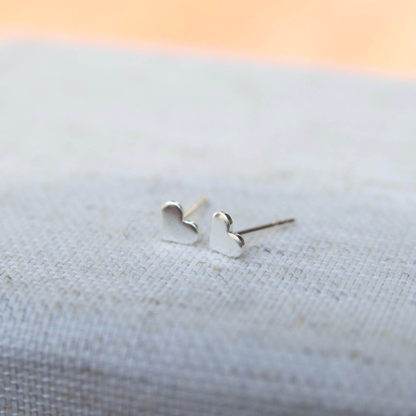 silver love heart stud earrings on grey background