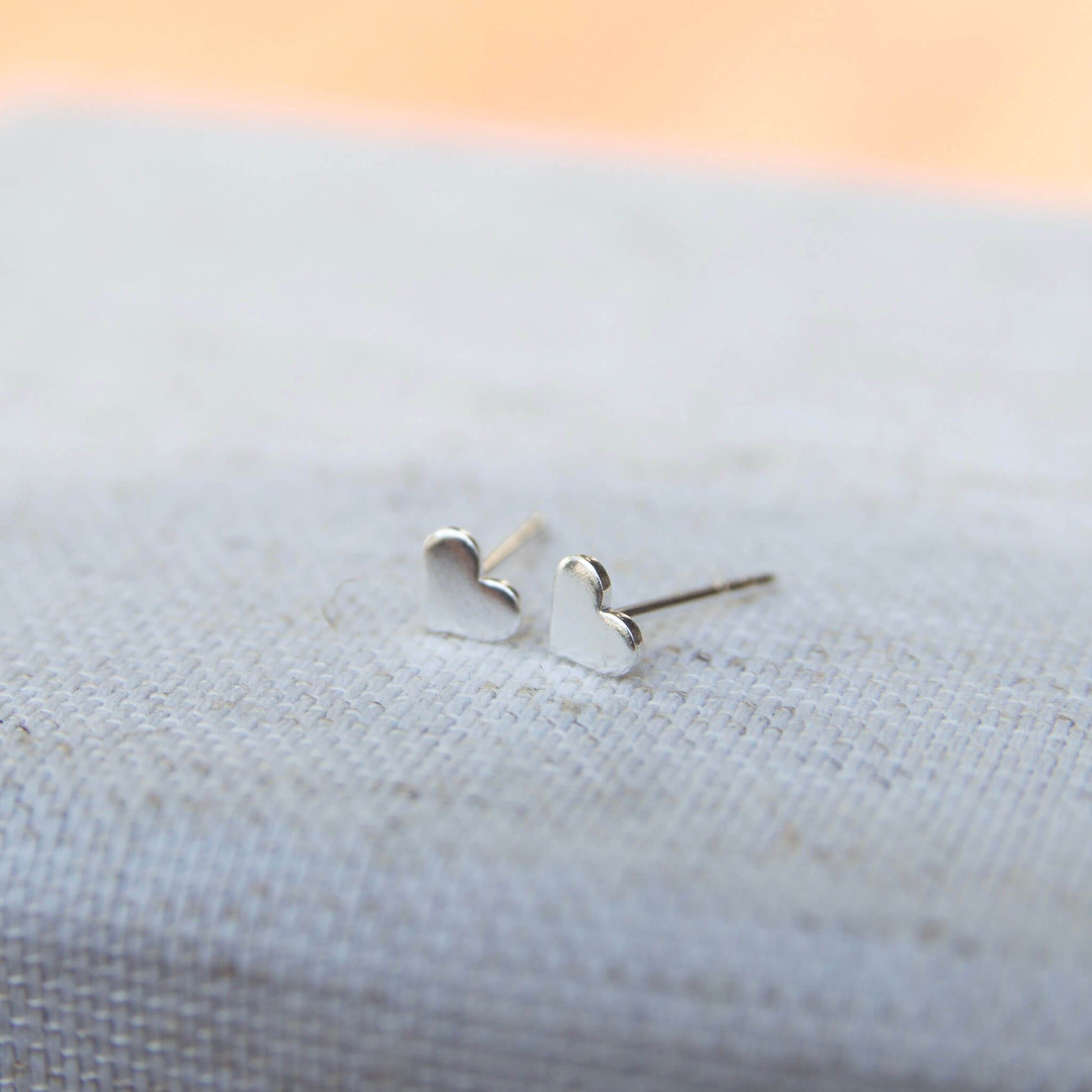 silver love heart stud earrings on grey background