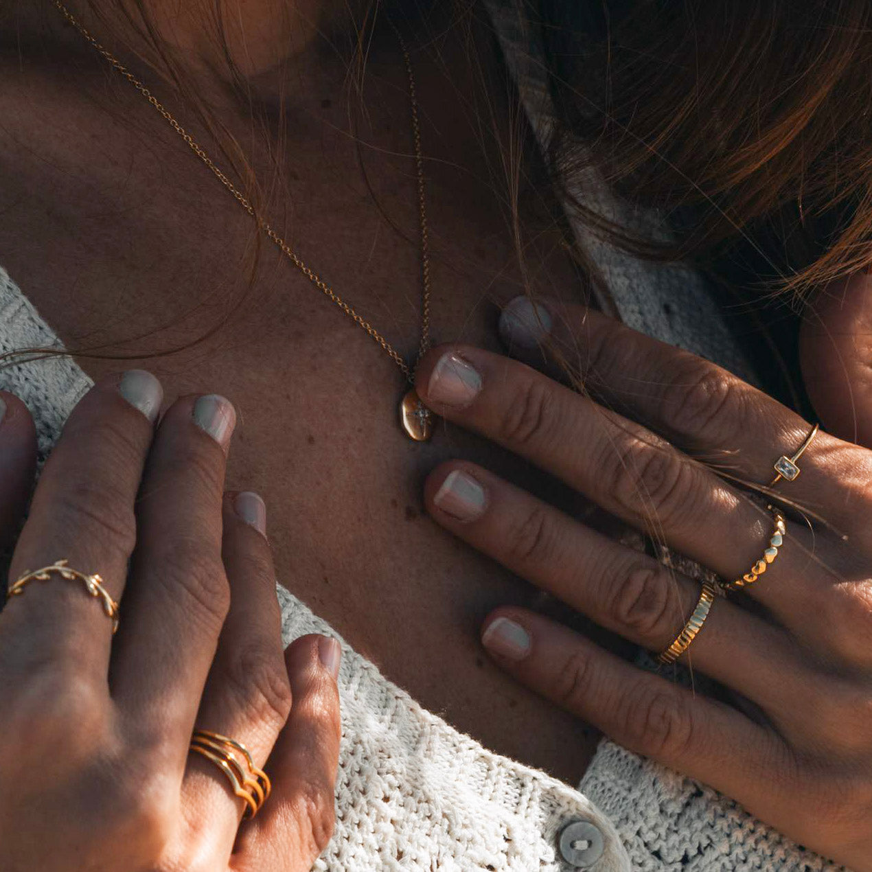 Close-up of hands with gold rings on a textured surface