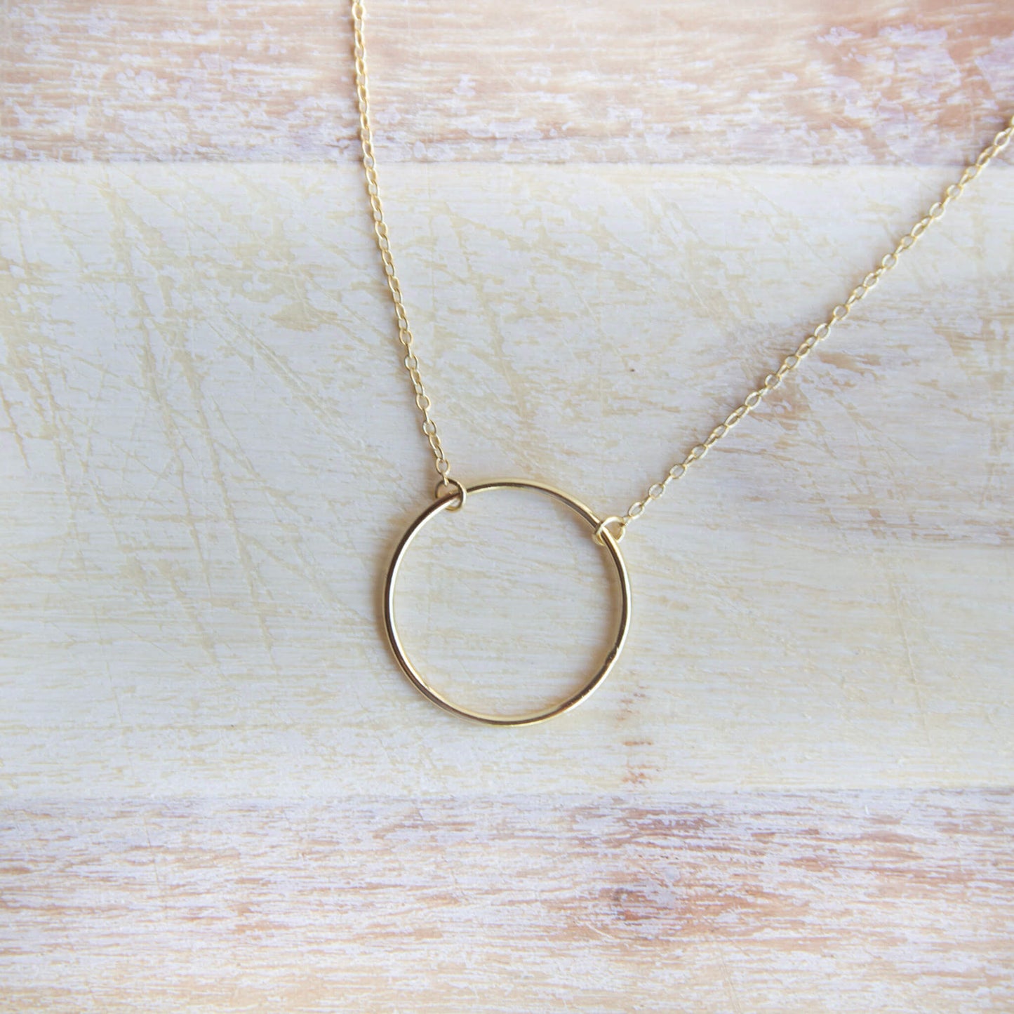 Gold Plated Circle Pendant Necklace on a wooden table