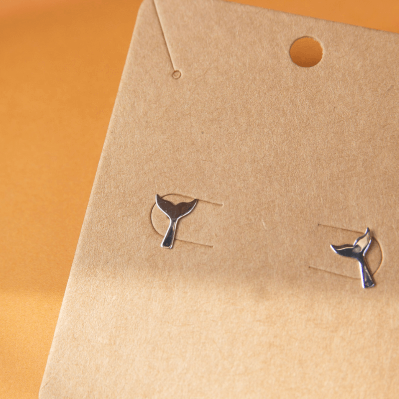 silver whale tail studs on cardboard