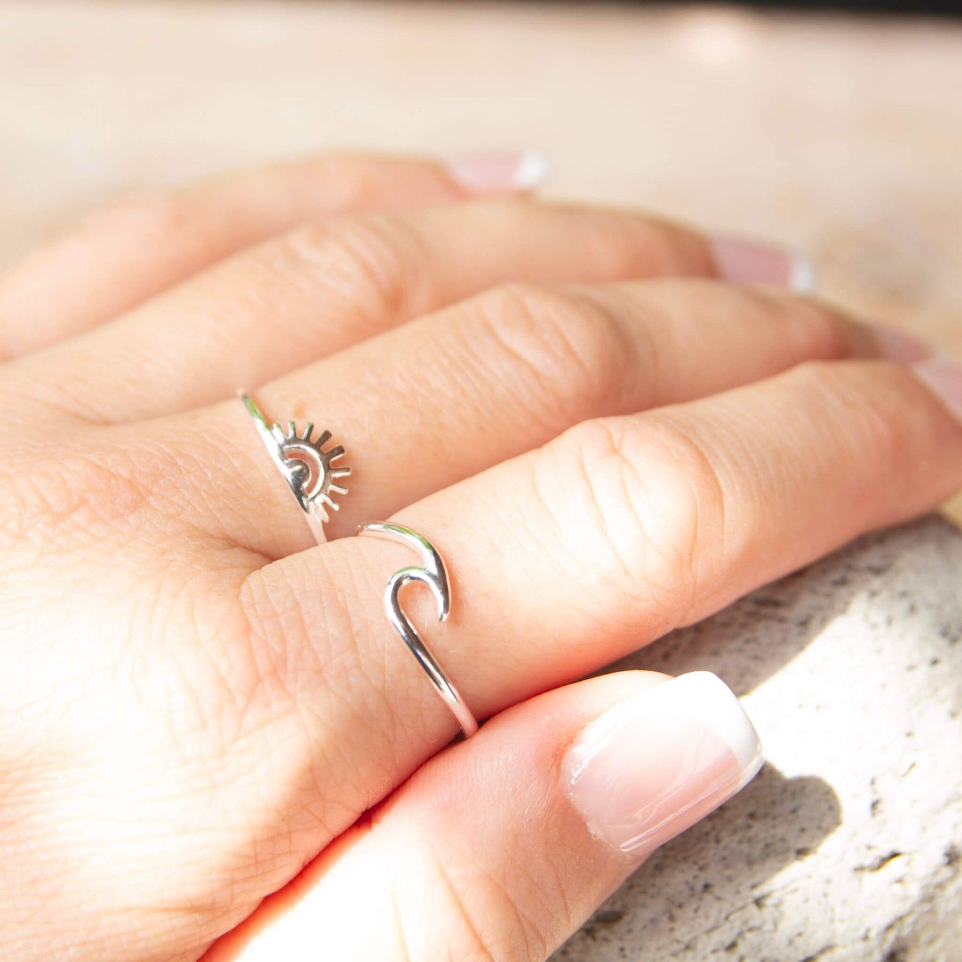 sunrise ring and wave ring on womans finger