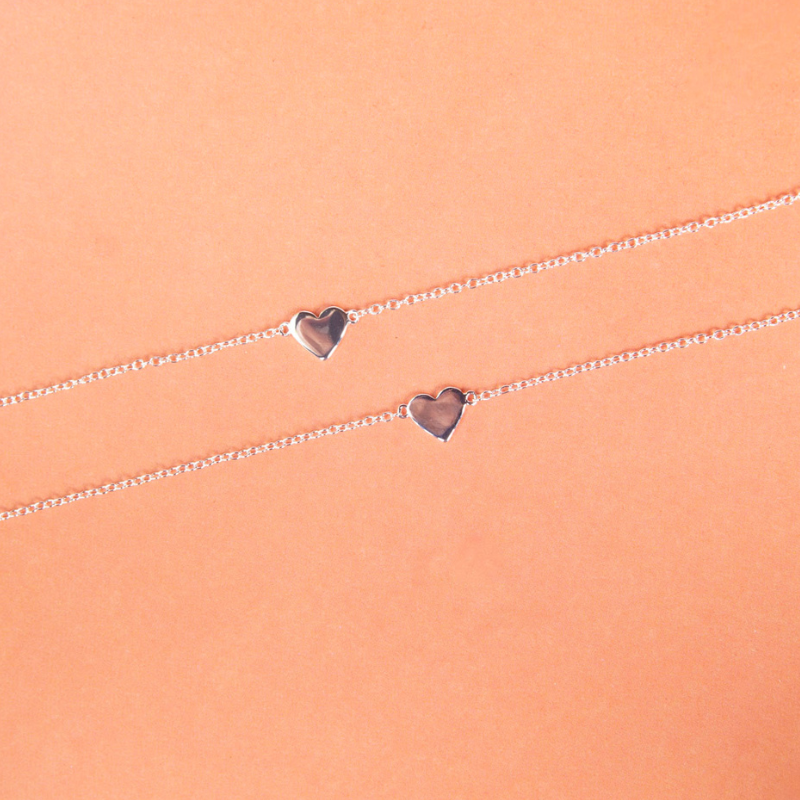 Silver bracelet with heart-shaped charms on a peach background