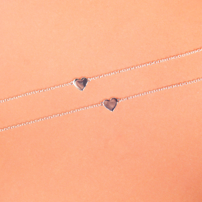 Silver bracelet with heart-shaped charms on a peach background