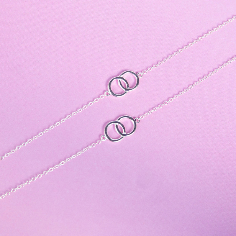 Silver necklace with interlocking rings on a light purple background