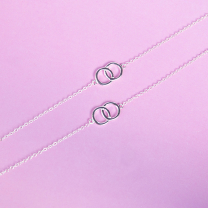 Silver necklace with interlocking rings on a light purple background