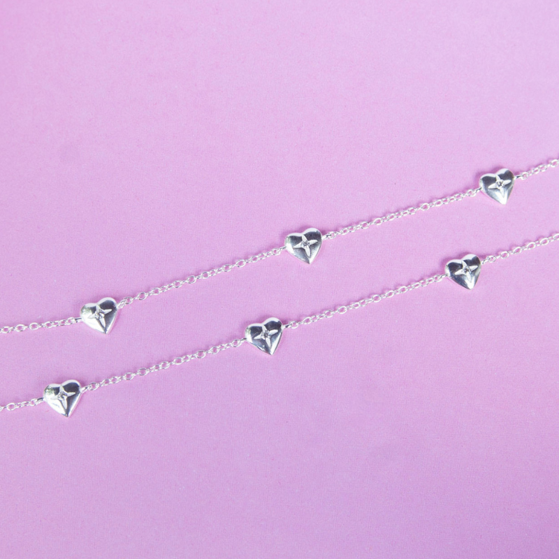 Silver heart-shaped necklace on a pink background