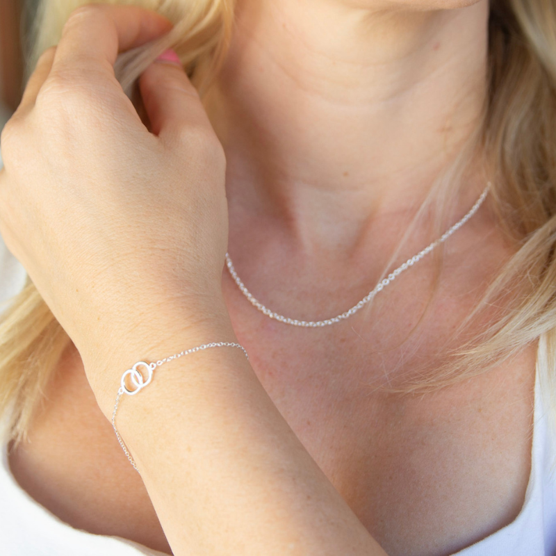 Close-up of a person wearing a silver necklace and bracelet.