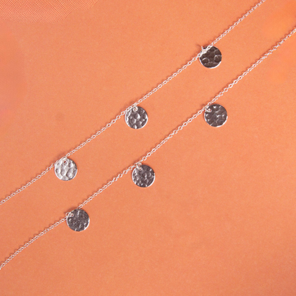 Silver bracelets with circular pendants on an orange background