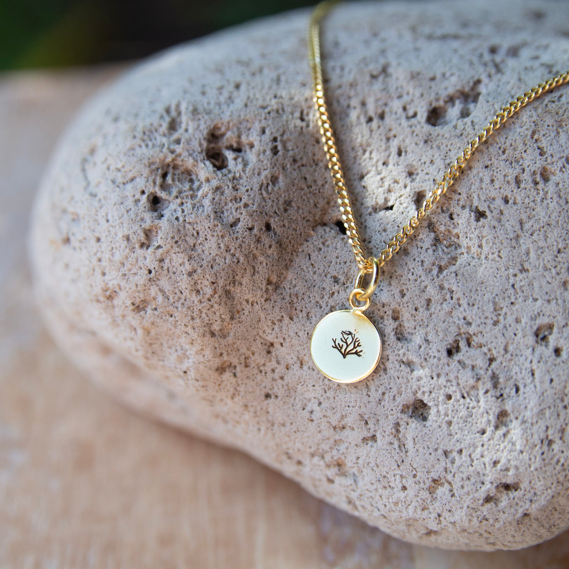 gold pendant with a coral stamped on it