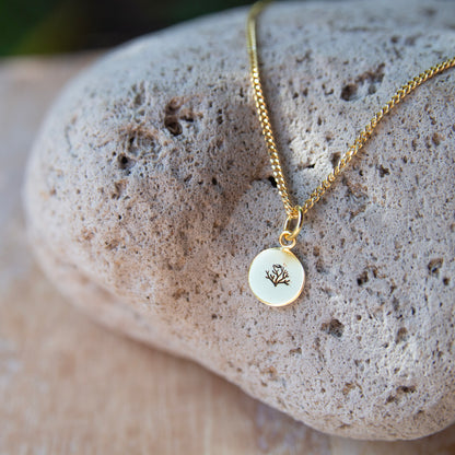 gold pendant with a coral stamped on it