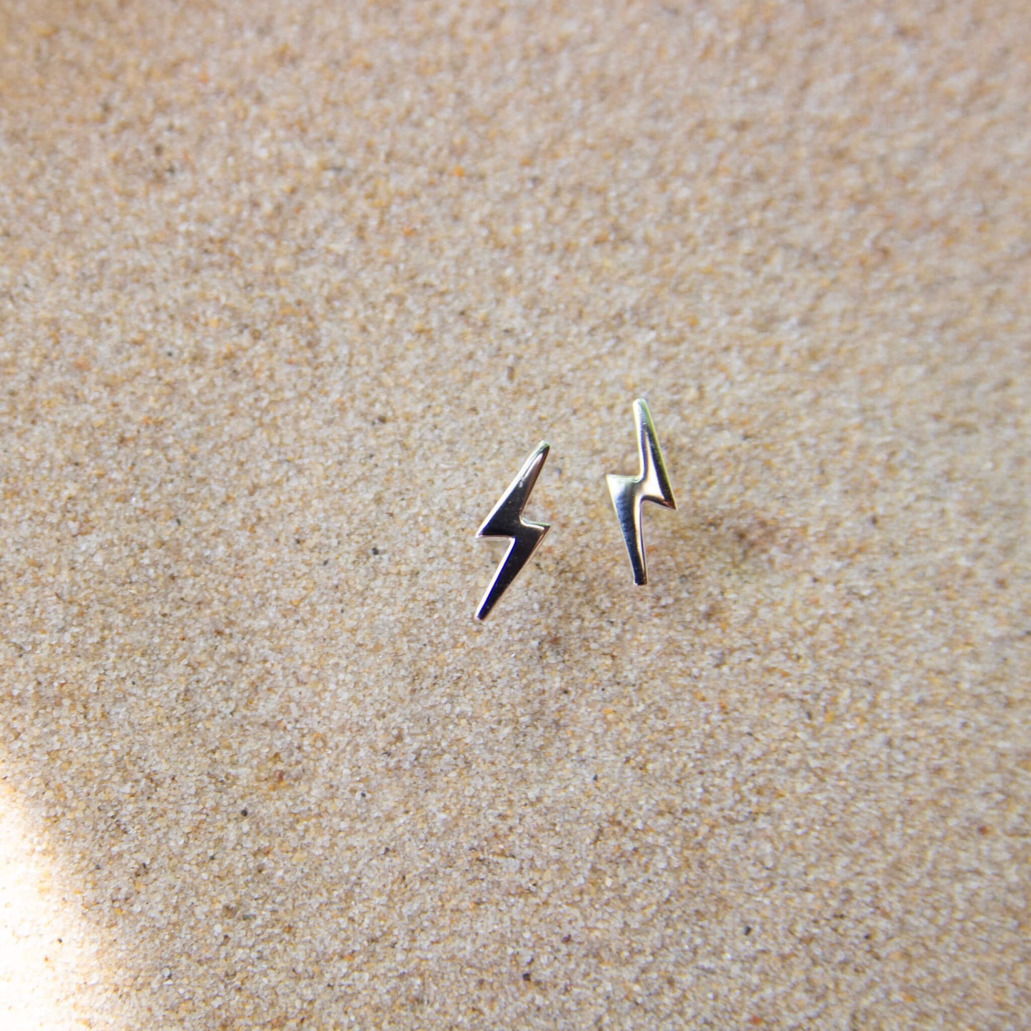 Silver bolt stud earrings in sand