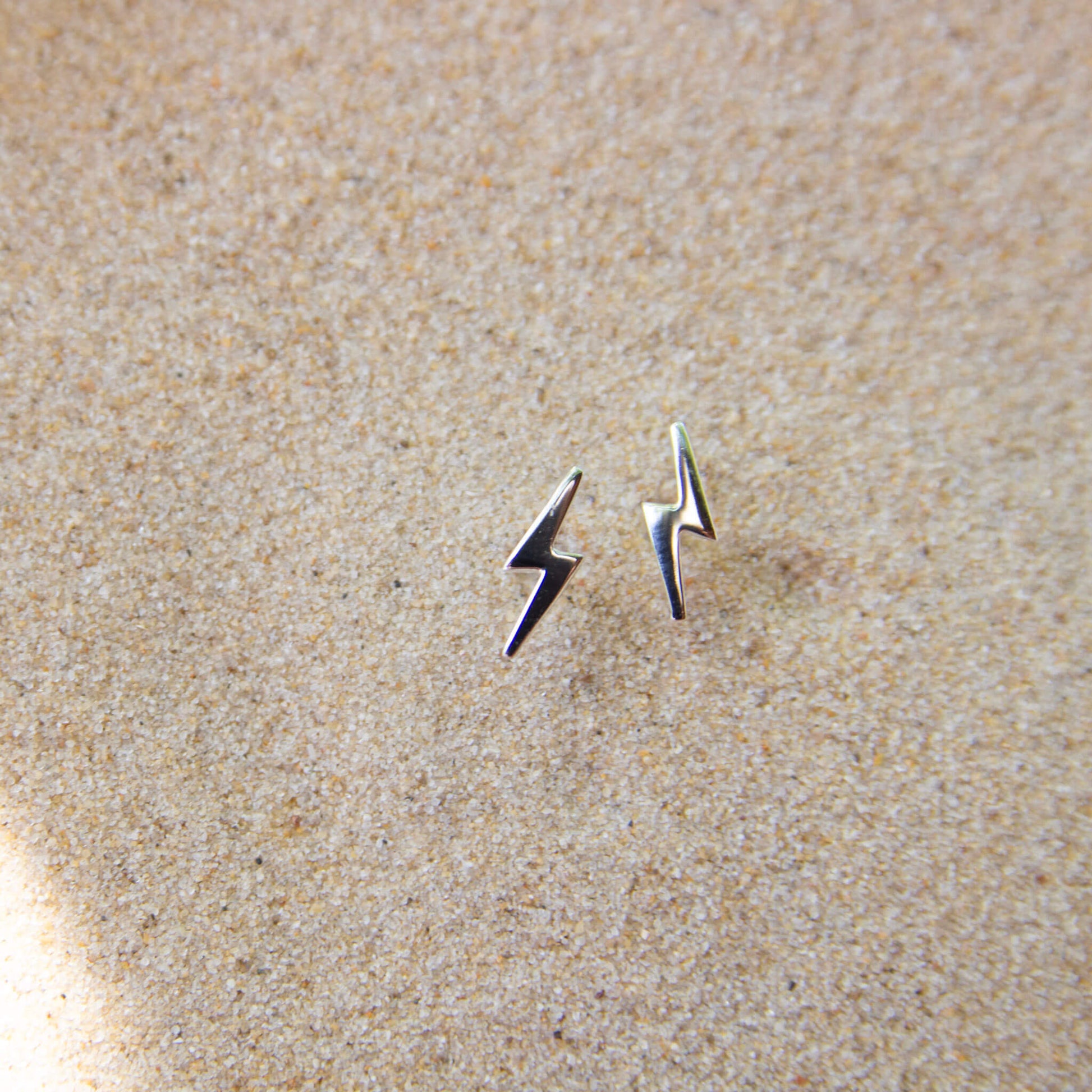 Silver bolt stud earrings in sand