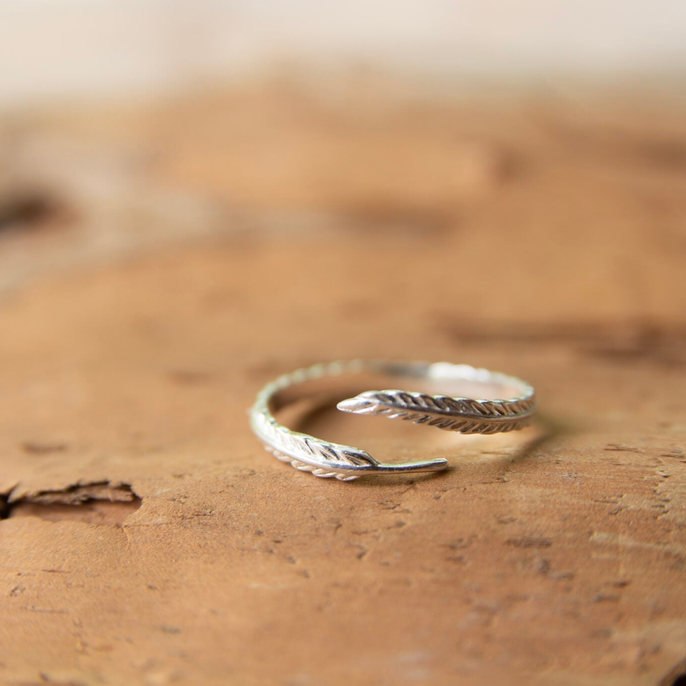 silver feather ring on a piece of bark