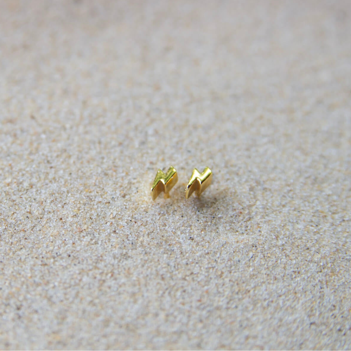 gold lightning bolt stud earrings in sand