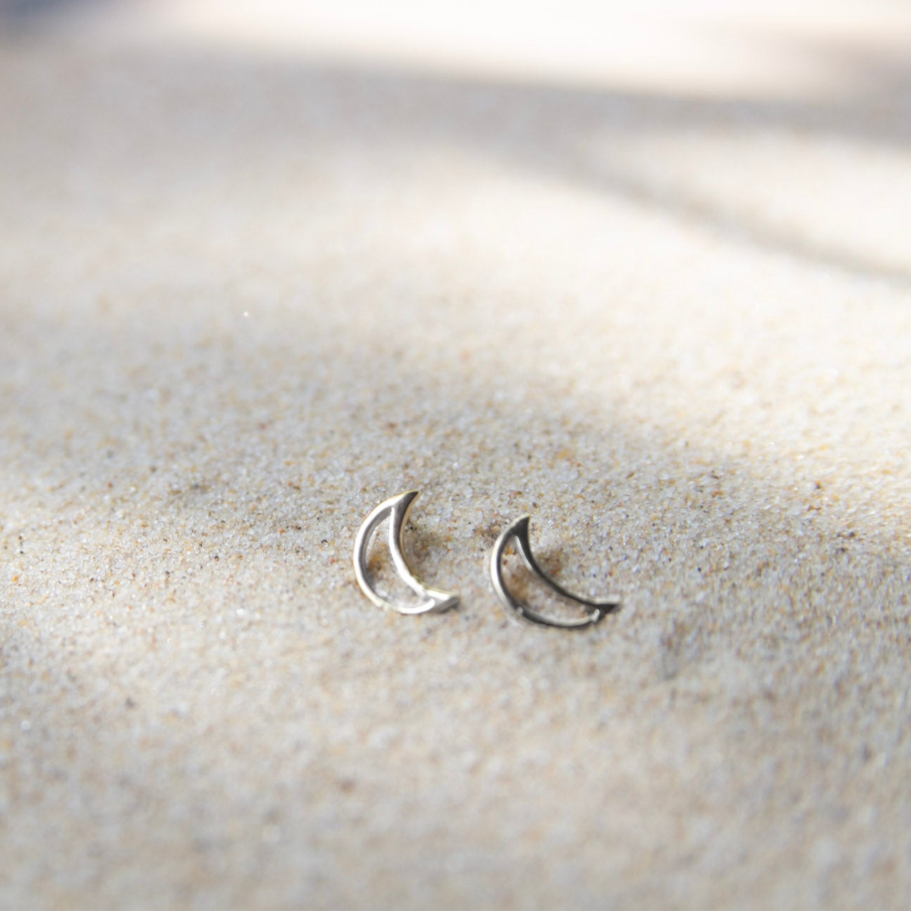 silver moon stud earrings on sand