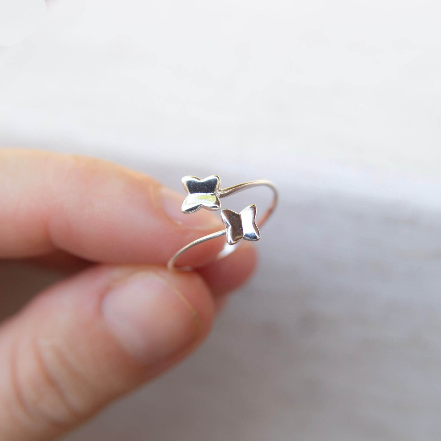 woman holding a silver butterflies wrap ring