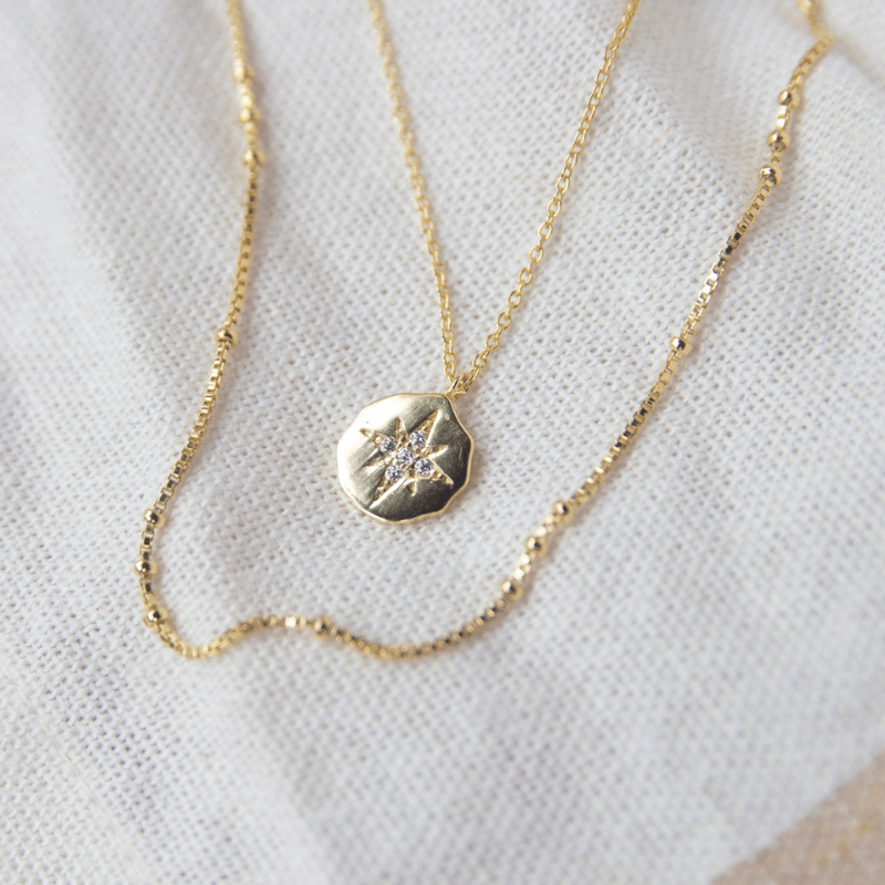 Gold necklace with a star pendant on a white fabric background