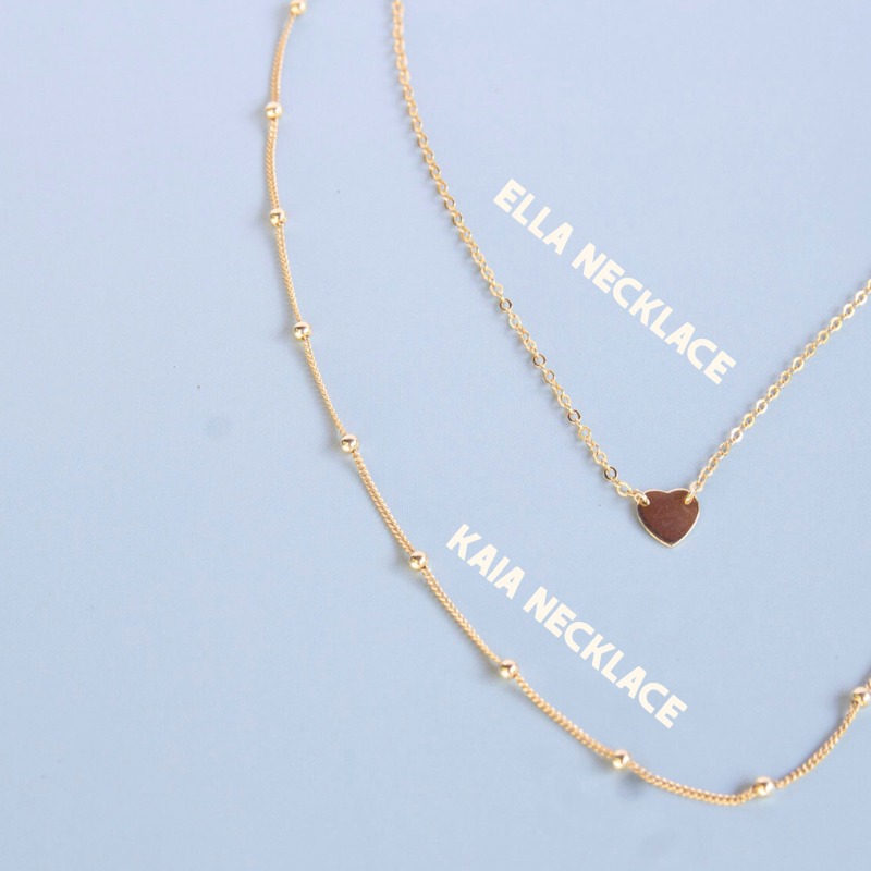 Two gold necklaces with 'Ella Necklace' and 'Kaia Necklace' labels on a light blue background.