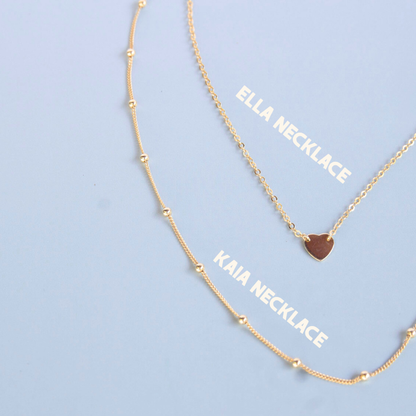 Two gold necklaces with 'Ella Necklace' and 'Kaia Necklace' labels on a light blue background.