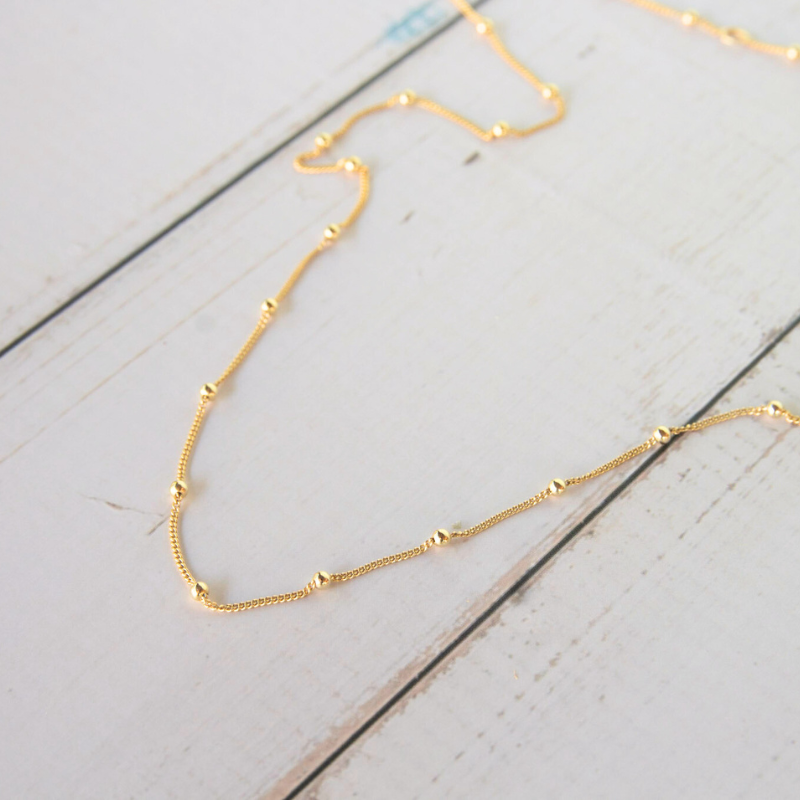 gold-plated necklace on white surface