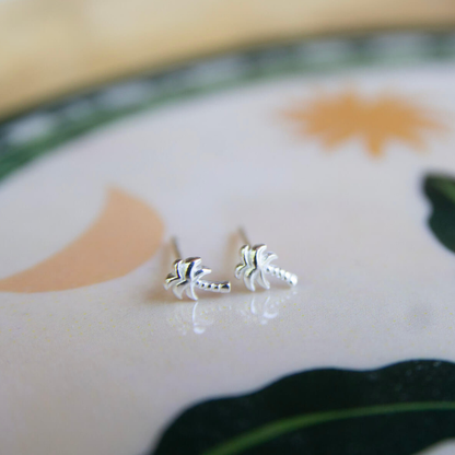 Silver palm tree earrings on a ceramic plate with floral design