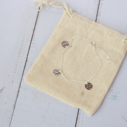 silver bracelet with hammered discs on a beige background