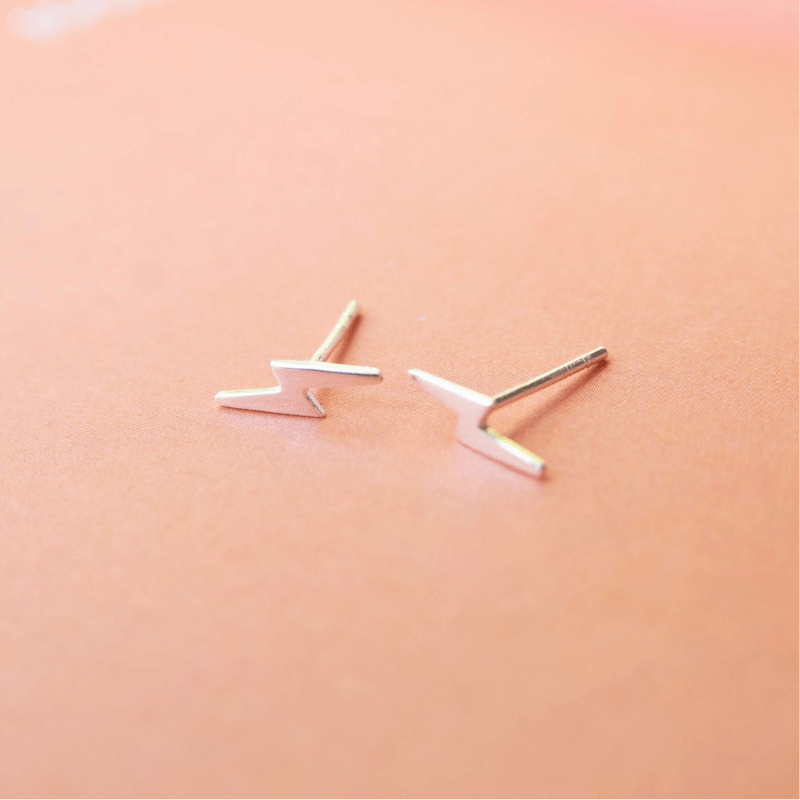 Pair of silver V-shaped earrings on a peach background