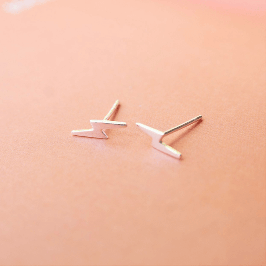 Pair of silver V-shaped earrings on a peach background