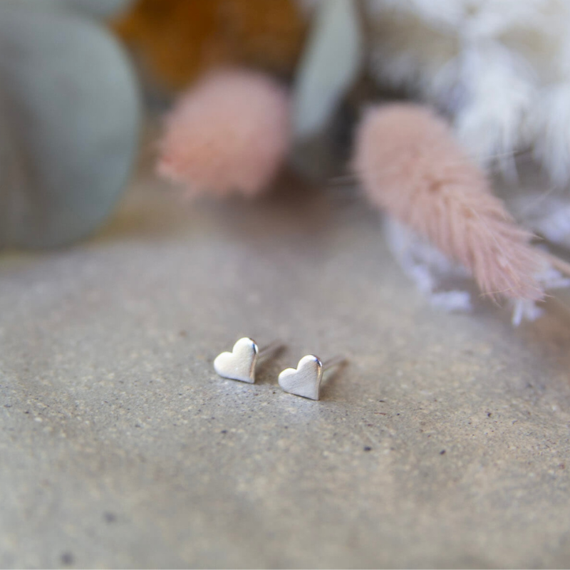Heart-shaped earrings on a textured surface with blurred background